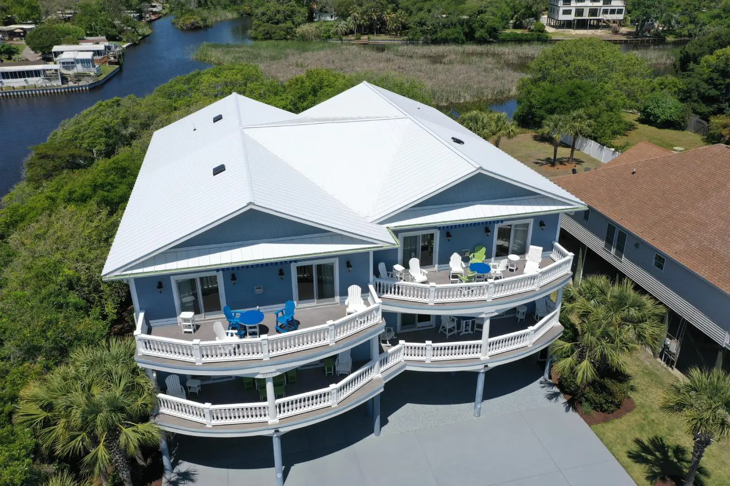 A large blue house with two balconies and a river in the background.