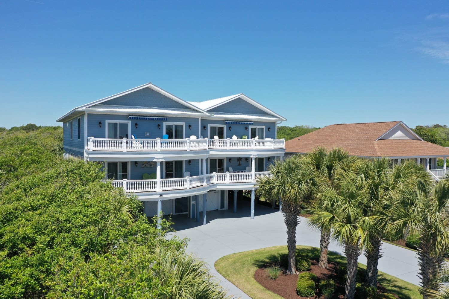 A large blue house with palm trees in the background.